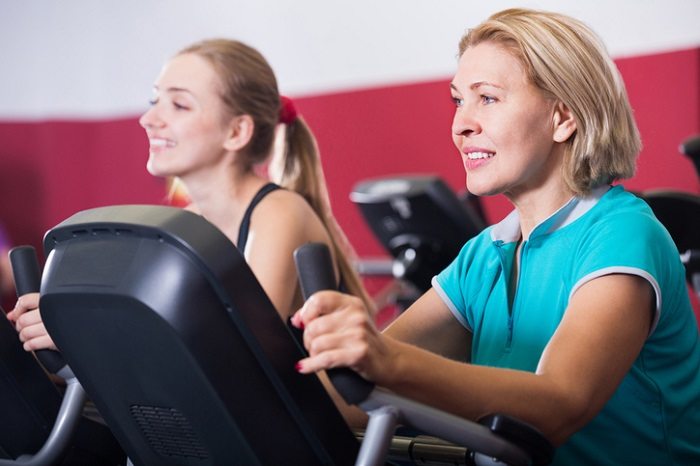 two women exercising on stair climbers at gym