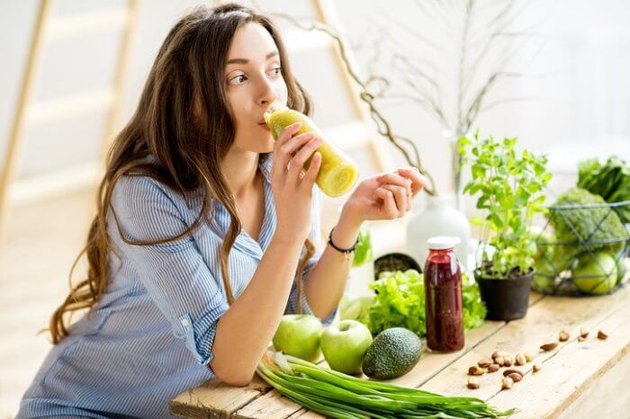 young woman drinking green vegetable smoothie