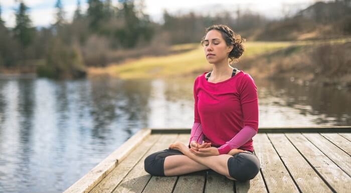 woman meditating on dock