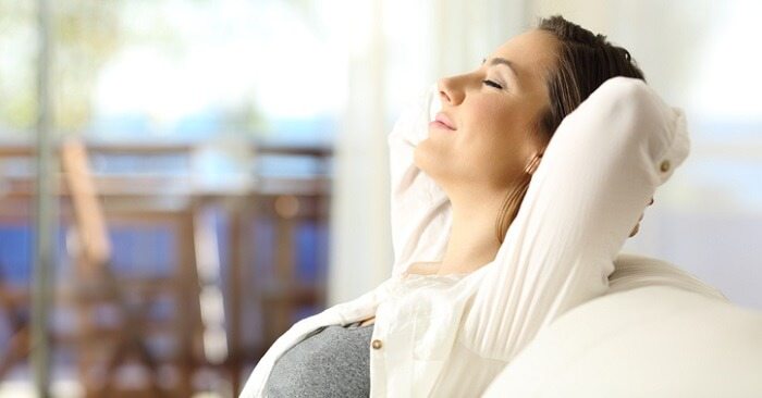 happy and relaxed woman sitting on couch