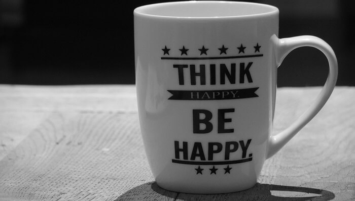 white coffee mug that says "think happy, be happy"