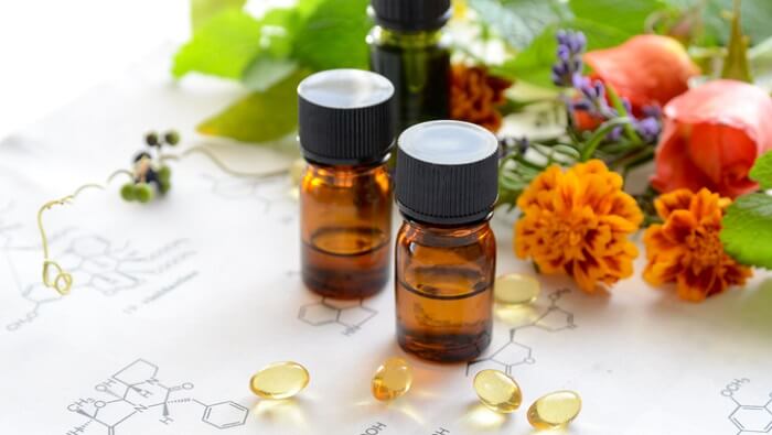 essential oils, herbs, supplements, and flowers on top of drawing of chemical structure