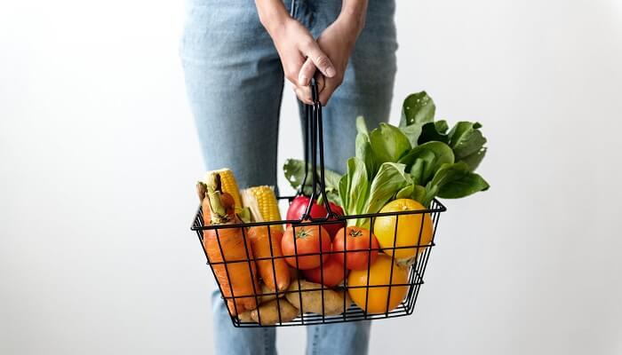 woman holding basket of fruits and vegetables