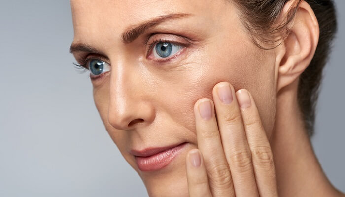 close up of middle-aged woman touching her face