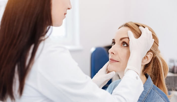 dermatologist checking woman's face