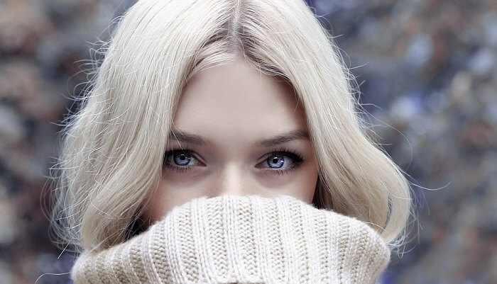 young blonde woman covering her face