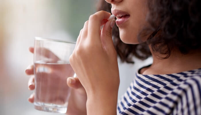 are essential oils safe to ingest concept - woman taking supplement