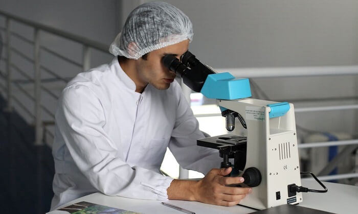scientist in lab looking at microscope
