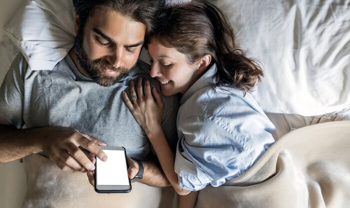 couple looking at cell phone in bed