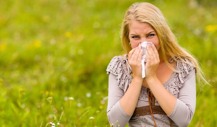 woman with allergies sneezing in field