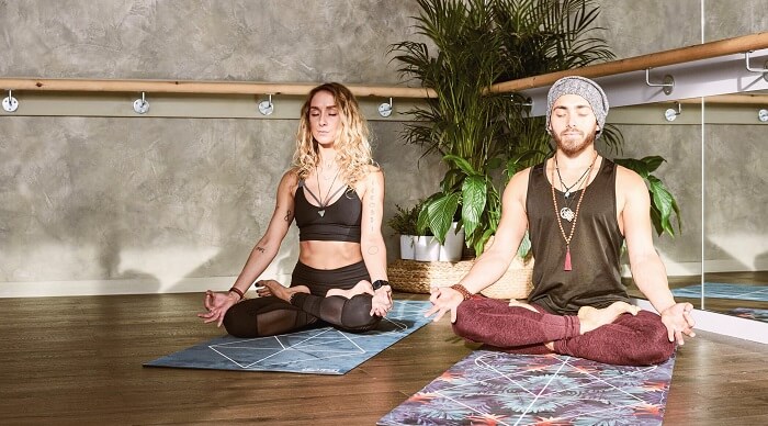 young man and woman meditating in yoga studio