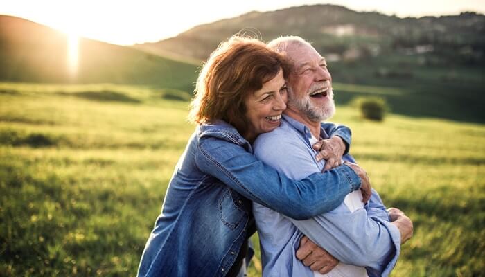 happy older couple hugging at sunset