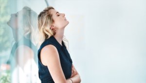 stressed-out young woman with back against office window