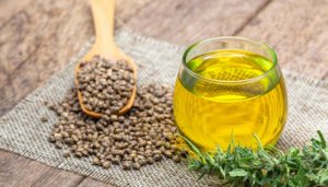 hemp seeds on wooden spoon and cbd oil bottle