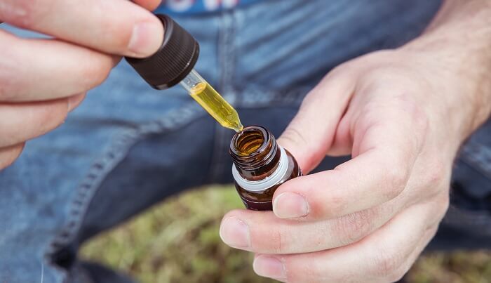 man using whole plant cbd oil dropper