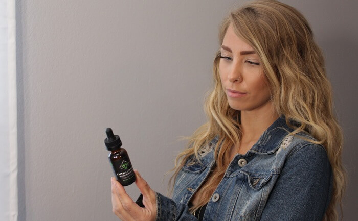 young woman reading label on whole plant cbd oil 