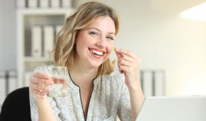 happy young woman taking omega 3 supplement