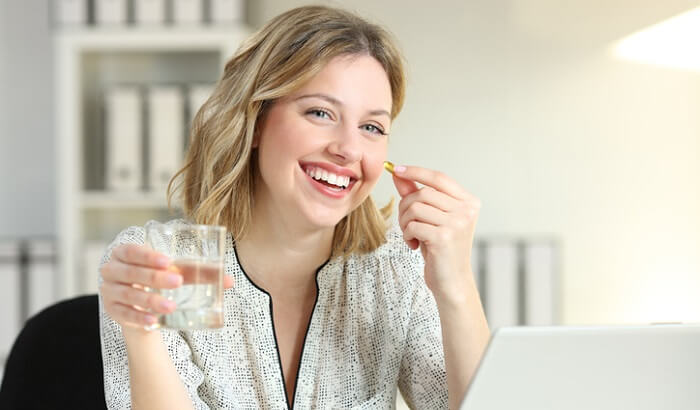 happy young woman taking omega 3 supplement