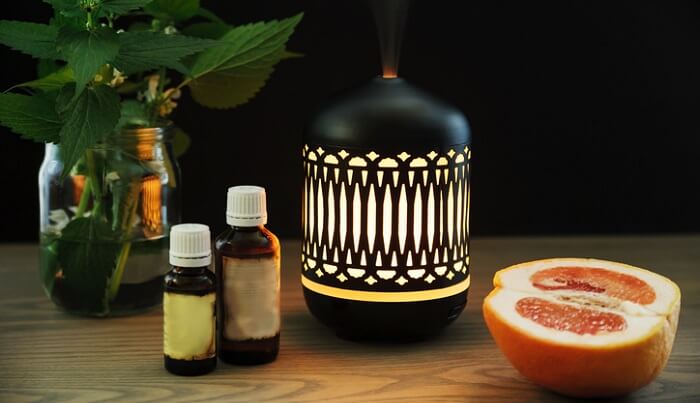 diffuser next to half grapefruit and essential oil bottles