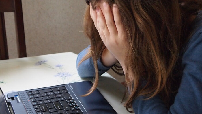 young girl covering face in front of computer