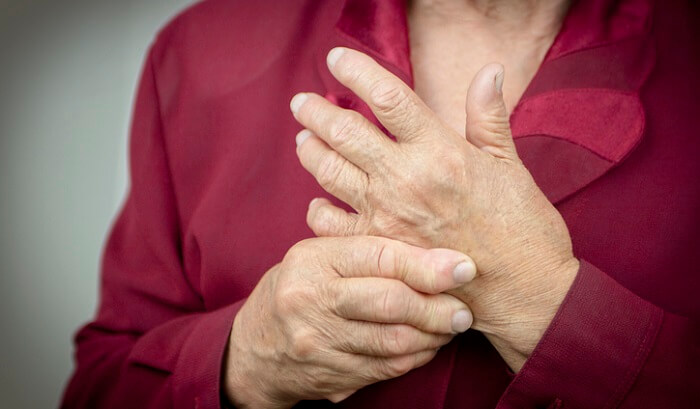 senior woman with rheumatoid arthritis rubbing hands