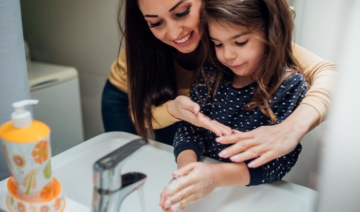 mother teaching young daughter to wash hands properly