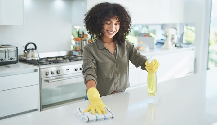 young woman cleaning with essential oils in kitchen