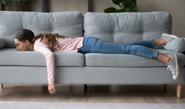 young fatigued woman sleeping with face down on couch