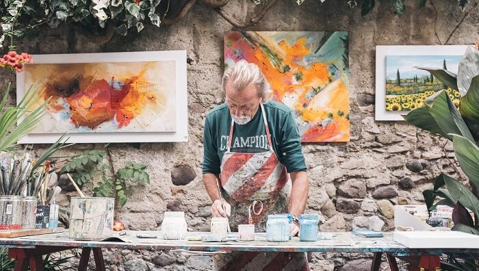 senior man painting pictures outside