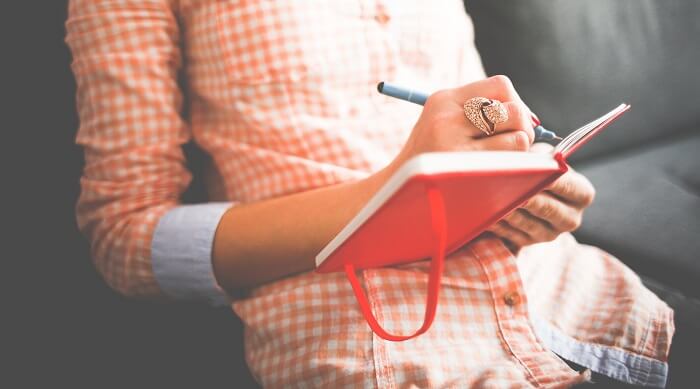 woman writing in red leather journal