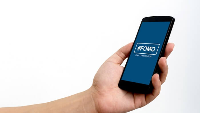 man holding phone with #fomo