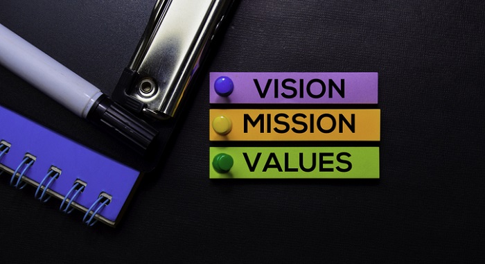 notebook and pen next to vision mission & values text