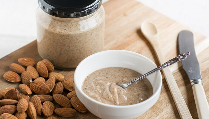 almonds next to bowl and jar of almond butter