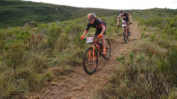 senior and young man biking in foothills