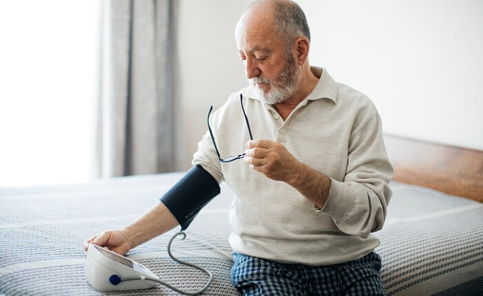 senior man taking blood pressure reading at home
