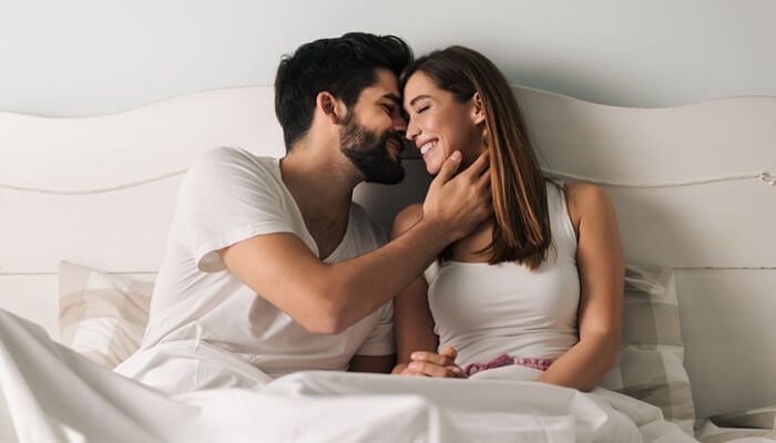 affectionate couple in bed - best essential oils for libido concept