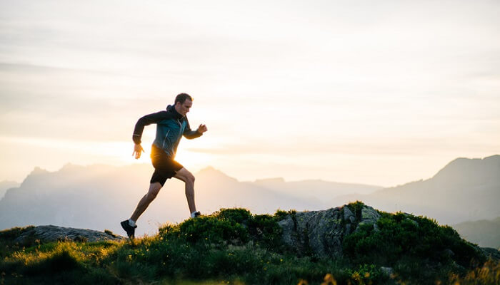 young man running on mountain ridge at sunrise