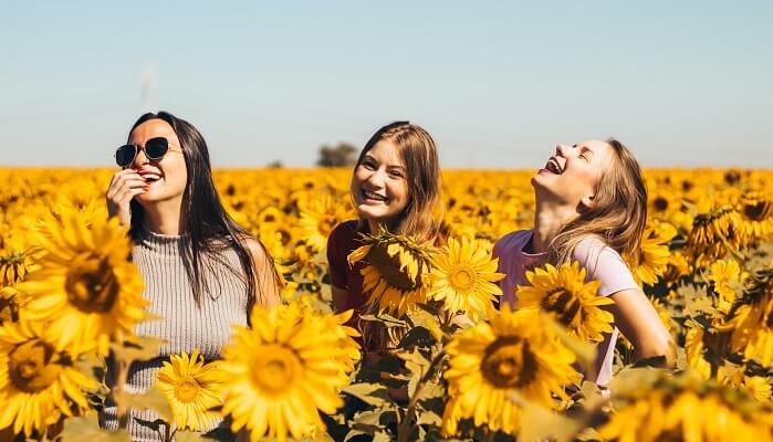 mother and daughters laughing in a field of dandelions