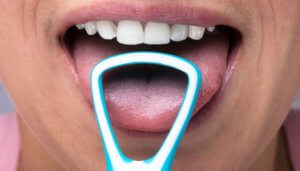 close up of person using tongue scraper