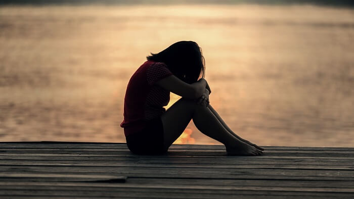 depressed woman with head down at sunset
