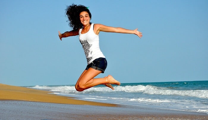 happy young woman jumping at beach