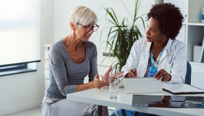 questions to ask your doctor concept - woman talking to doctor