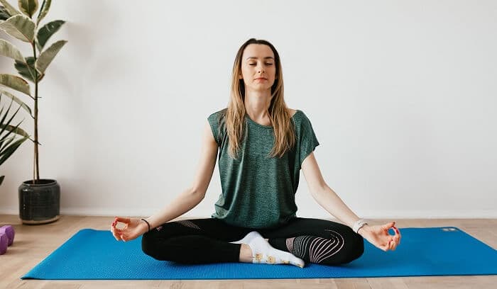 young woman meditating on yoga mat
