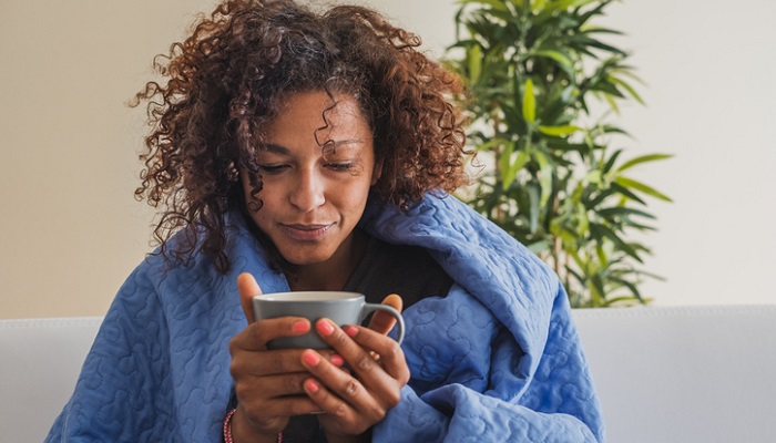 ill woman in blanket drinking tea