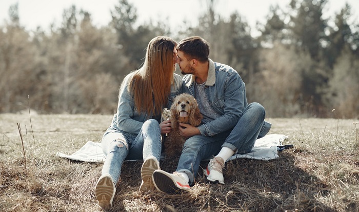 happy couple sitting on blanket in outdoors with dog