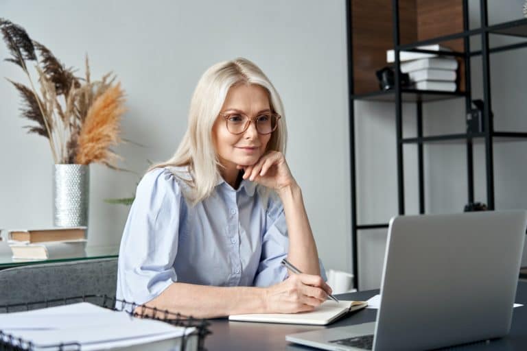 middle-aged woman watching professional training class and taking notes