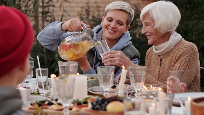 smiling woman pouring a drink for happy senior woman at dinner table