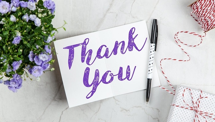 thank you card next to flowers and gift