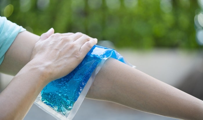 woman placing ice pack on her arm