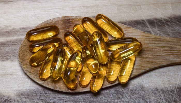 omega 3 pills on wooden spoon